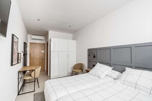 Een moderne slaapkamer met een groot bed, een bureau en een stoel.
