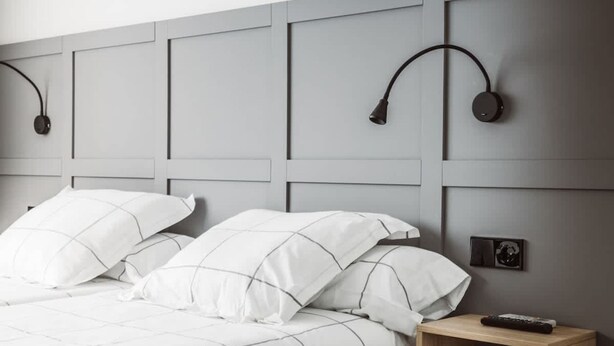 A modern bedroom with a bed, headboard, bedside table, and wall-mounted lamp. - Chamberi Business Studio (Madrid)