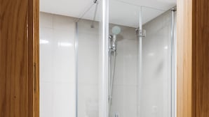 A modern bathroom with a glass-enclosed shower, a white toilet, and a white sink. - Chamberi Business Studio (Madrid)