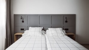 A double bed with a grey headboard, two bedside tables, and a light fixture on each side. - Chamberi Business Studio (Madrid)