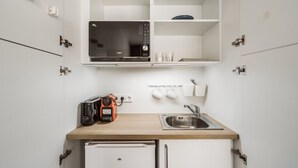 A compact kitchenette with a microwave, toaster, sink, and a small refrigerator. - Chamberi Business Studio (Madrid)
