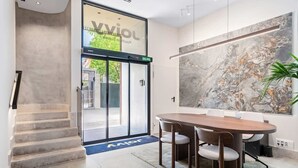 A modern hotel lobby with a large marble wall, a wooden conference table with chairs, and a staircase leading to an outdoor area. - Pac Fico Suite With Single Sofa Bed Near Retiro (Madrid)