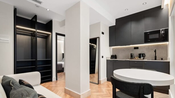 A modern kitchen with dark cabinetry, a white countertop, and a microwave. - Pac Fico Suite With Single Sofa Bed Near Retiro (Madrid)