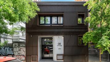 Un edificio moderno con fachada oscura, entrada visible y un coche estacionado afuera.