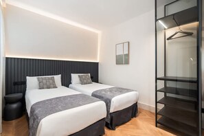 Una moderna camera d'albergo con due letti, un comodino, un armadio e un guardaroba.