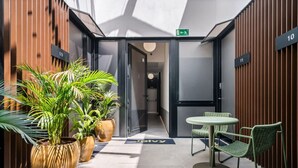 En modern hotellobby med ett glastak, krukväxter, en receptionsdisk och en sittgrupp.
