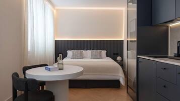 A modern hotel room with a bed, bedside table, and a small round table with chairs.