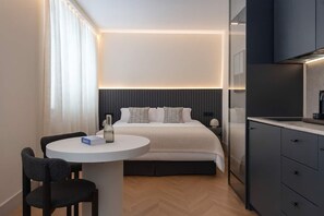 A modern hotel room with a bed, bedside table, and a small round table with chairs. - Pac Fico Patio Suite Near Retiro (Madrid)