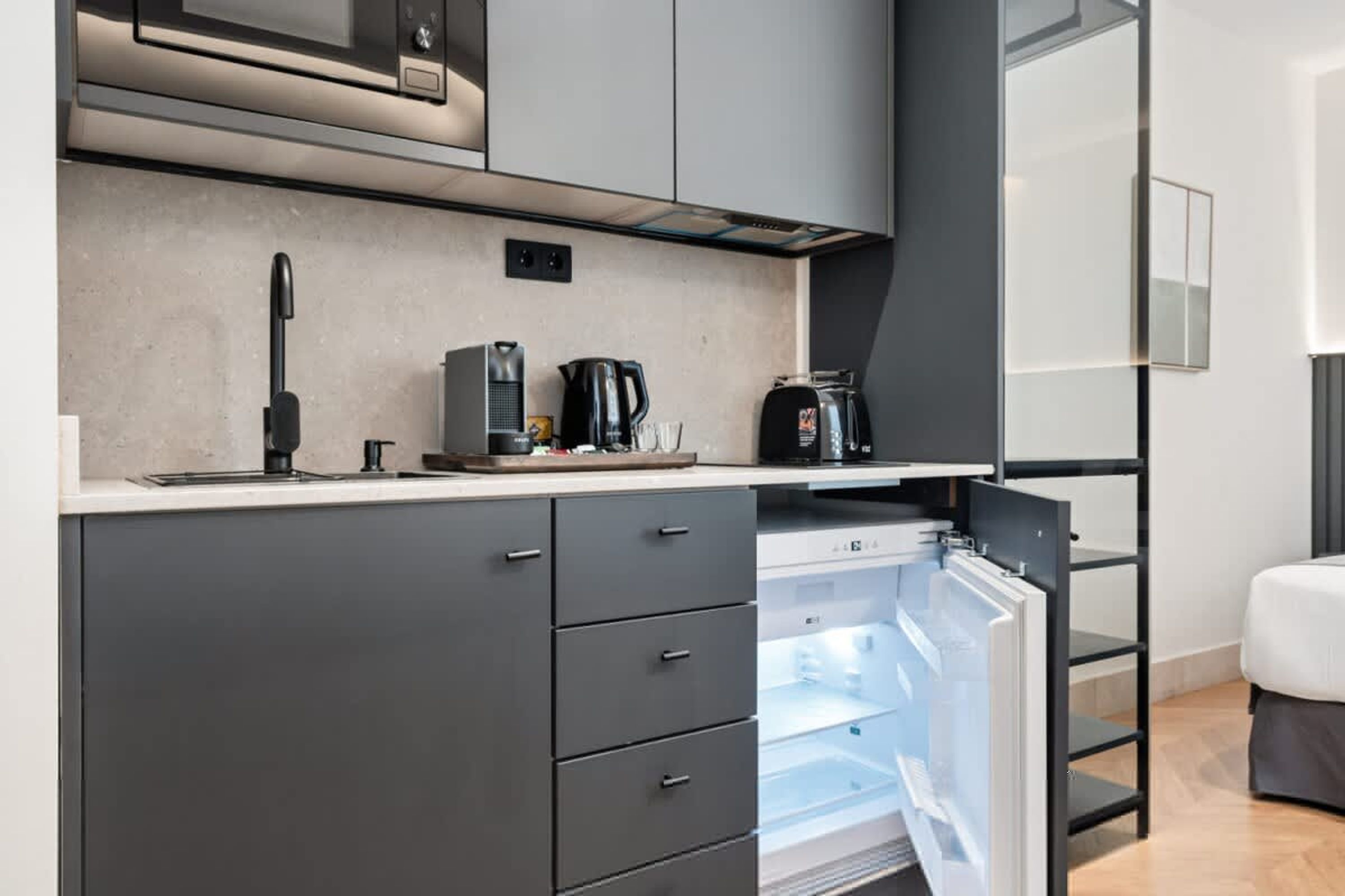 A modern kitchen with a built-in microwave, coffee maker, and a refrigerator with a water dispenser.