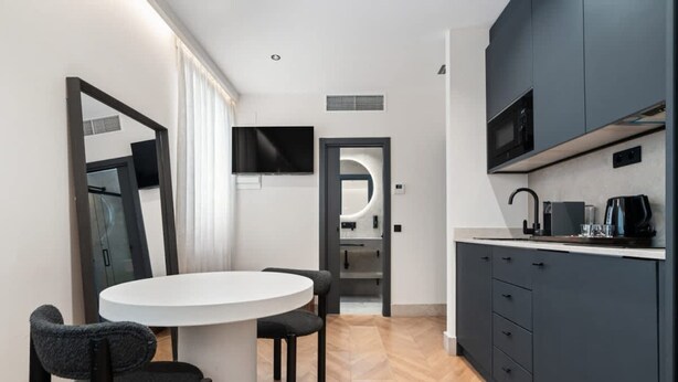 A modern kitchen with dark cabinets, a white countertop, and a built-in microwave. - Pac Fico Deluxe King Suite Near Retiro (Madrid)
