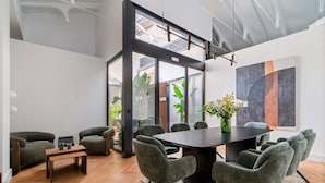 A modern meeting room with a large table, grey upholstered chairs, and a glass partition. - Pac Fico Deluxe King Suite Near Retiro (Madrid)