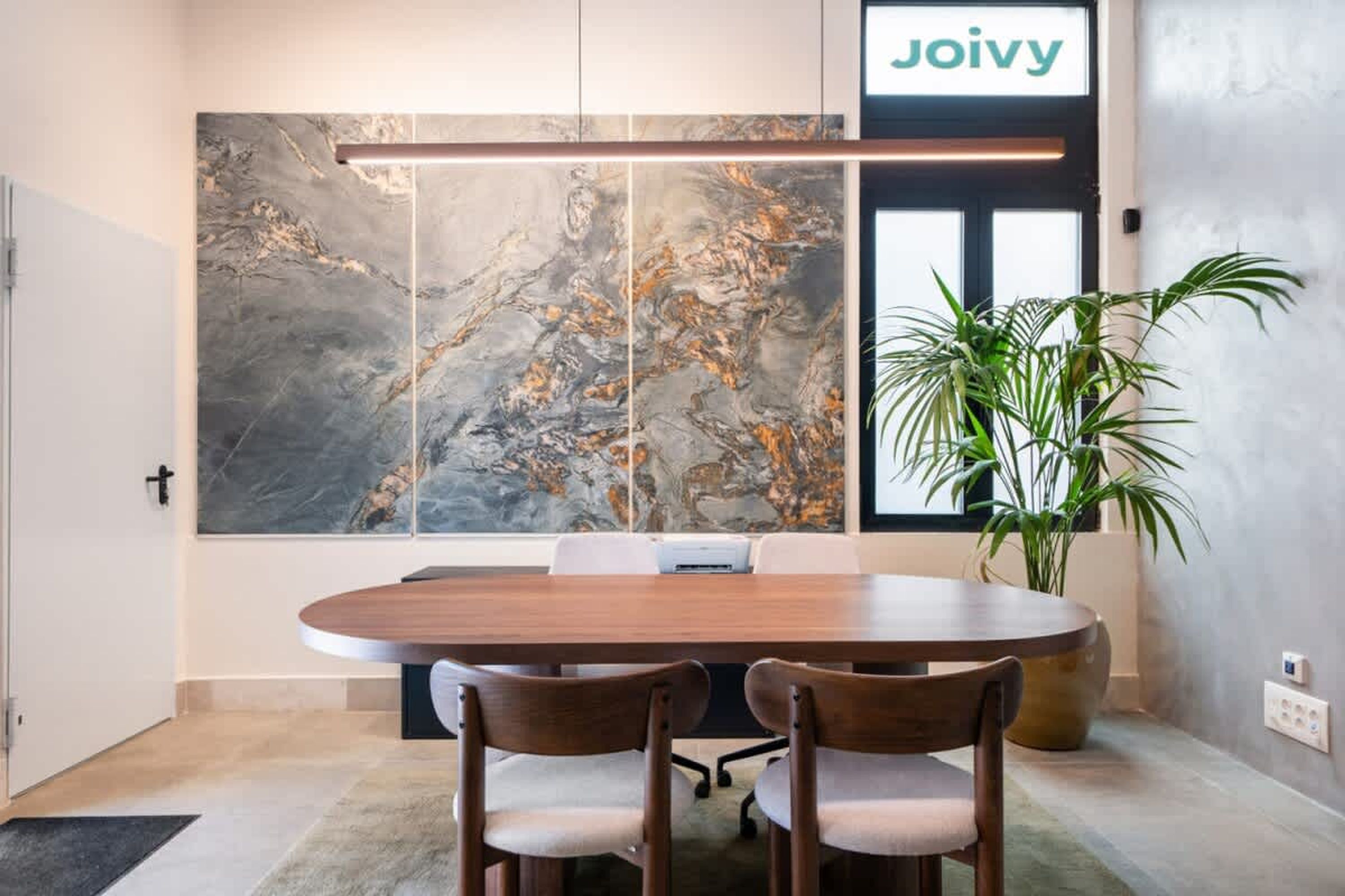 A conference room with a large abstract painting, a wooden table, and two chairs.