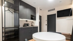 A modern kitchen with dark cabinets, a white countertop, and a round dining table with a chair. - Pacifico Deluxe Double Suite Near Retiro (Madrid)