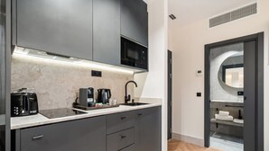 A modern kitchen with dark cabinetry, a microwave, a coffee maker, and a toaster. - Pacifico Deluxe Double Suite Near Retiro (Madrid)