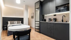 A compact, modern hotel room with a bed, bedside table, and a small dining area. - Pacifico Deluxe Double Suite Near Retiro (Madrid)