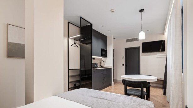 A modern hotel room with a bed, a small dining table, and a kitchenette. - Pacifico Deluxe Double Suite Near Retiro (Madrid)