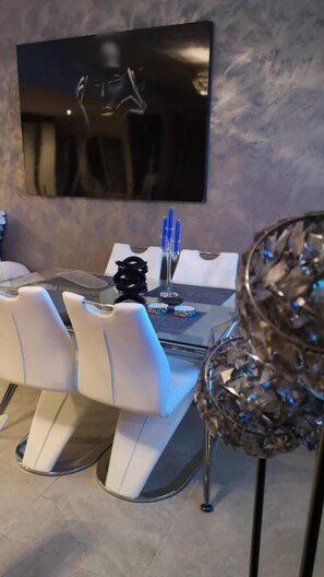 Un espace repas avec une table moderne, des chaises blanches et une sculpture en verre décorative.