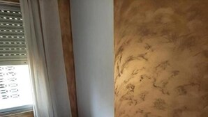 A small, neatly made bed with a white bedspread and pillows, a rolled towel on the side, and a window with blinds partially open. - Seaside Bliss Apartment in Daimus (Daimuz)