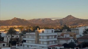 A residential area with modern buildings, a prominent mountain range in the background, and a clear sky. - Seaside Bliss Apartment in Daimus (Daimuz)