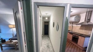Un pasillo que conduce a una cocina con piso de baldosas y un comedor con una mesa y sillas.