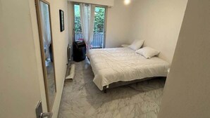 Un dormitorio con una cama, una ventana con cortinas y una lámpara en el techo.