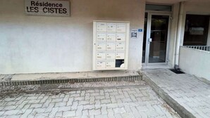 Entrada de un edificio con un buzón y un cartel que dice "Résidence LES CISTES".