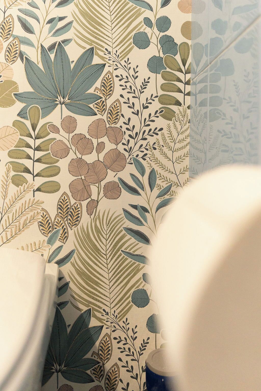 Een badkamer met behang met bloemenprint en een witte badkuip.