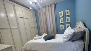 A bedroom with a bed, a wardrobe, a bedside table, and a ceiling light fixture. - Beautiful spacious flat in the old town of Ivrea (Ivrea)