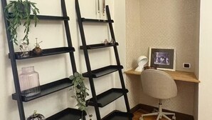 A corner office with a desk, chair, and two black shelving units against the wall. - Beautiful spacious flat in the old town of Ivrea (Ivrea)
