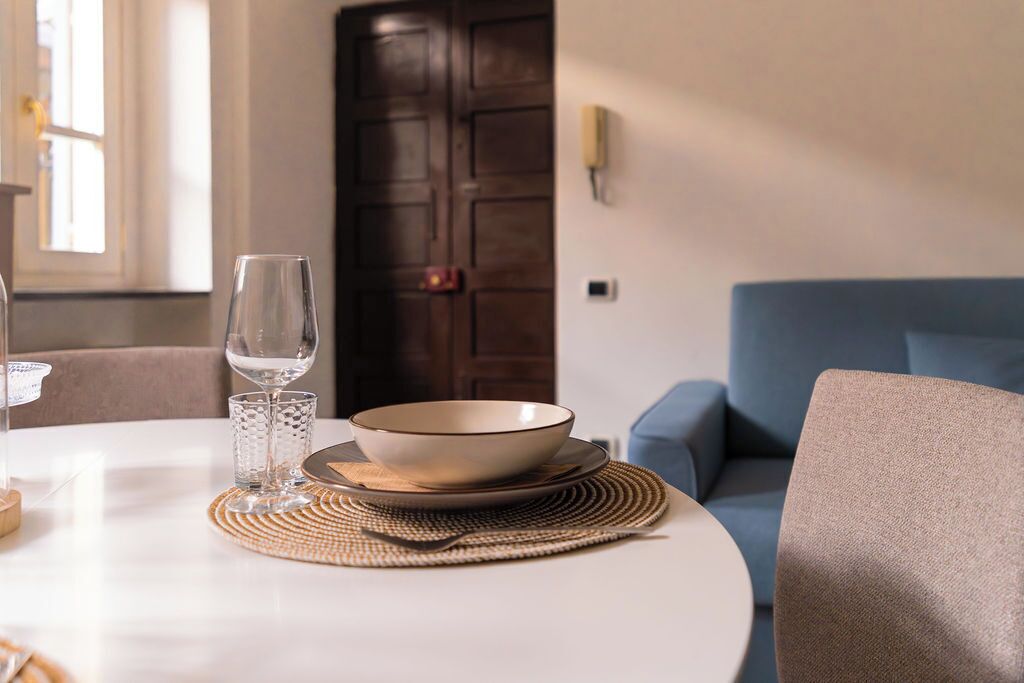 A dining table with a bowl and glass, a woven placemat, and a blue sofa in the background.