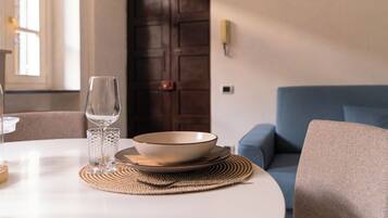 A dining table with a bowl and glass, a woven placemat, and a blue sofa in the background.