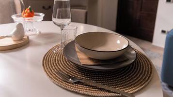 A dining table set with a bowl, plates, a glass, and a fork on a woven placemat.