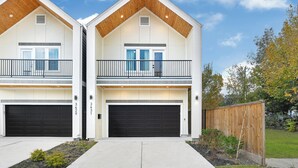 Ett modernt hus i två våningar med garage, balkong och en välskött trädgård framför huset.