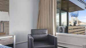 Een hotelkamer met een groot raam, een stoel, een bureau en een bed.