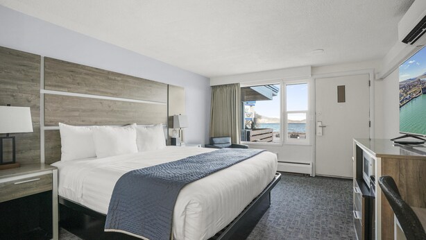 Een hotelkamer met een bed, een bureau, een televisie en uitzicht op de oceaan.