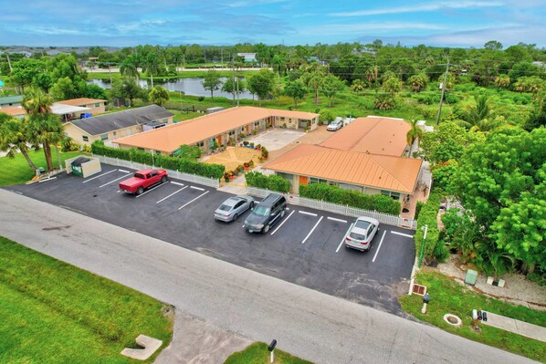 A motel with multiple parking spaces and a covered parking area. - Paradise Inn of Naples (Naples)