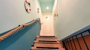 Una escalera con barandilla, una puerta blanca al final y una pared con un adorno circular.