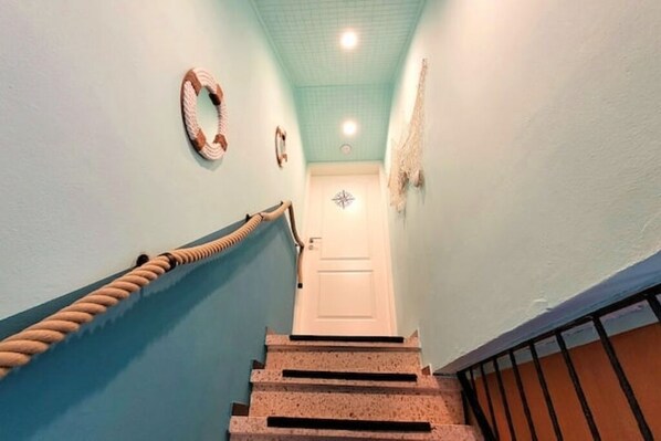 A staircase with a handrail, a white door at the top, and a wall with a circular decoration.