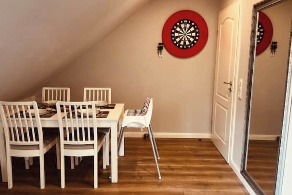 Un espace repas comprenant une table et des chaises, un jeu de fléchettes et une porte.