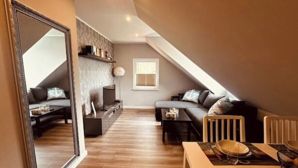 Un loft moderno con un espejo grande, una zona de estar acogedora y un comedor.