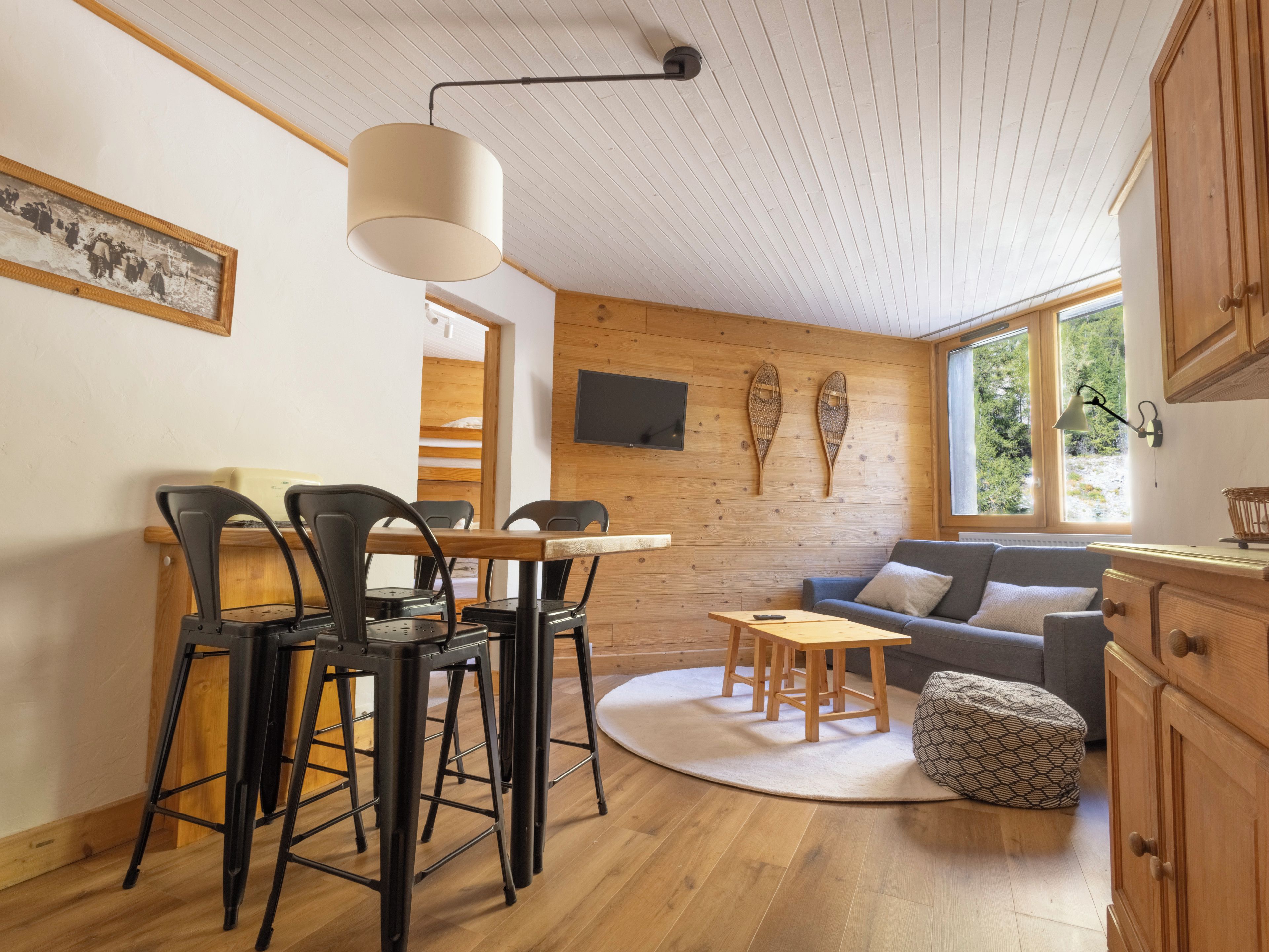 A cozy room with a dining area, a sofa, and a TV mounted on the wall.