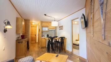 A cozy room with a wooden dining table, a sofa, and a kitchen area with wooden cabinets and a microwave.