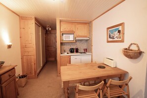 Eine kompakte Küche mit Holzausstattung, einer Mikrowelle, einem Spülbecken und einem Essbereich mit Tisch und Stühlen.