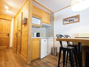 A compact kitchen with wooden cabinets, a microwave, a coffee maker, and a trash bin. - Val Snow 210 Cosy and Practical Apartment in the Heart of Val d’Isère (Val-d'Isère)