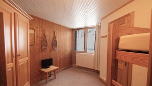 Puisilla paneeleilla verhoiltu huone, jossa on pienellä pöydällä televisio, ikkunasta avautuva näkymä ja patteri.