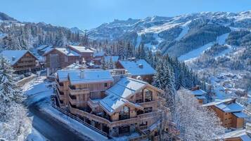 A large wooden lodge with multiple balconies and a ski slope in the background.