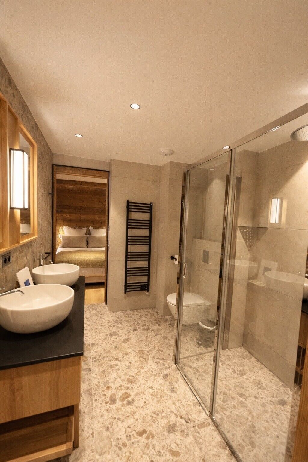 A modern bathroom with a large sink, a glass shower enclosure, and a wooden vanity.