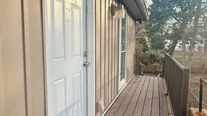A wooden deck with a white door and a small rug. - Lee's Summit Loft-near downtown (Lee's Summit)