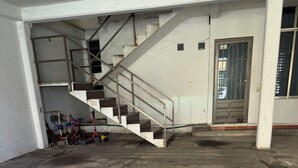 A spacious, unfinished interior with a concrete floor, a staircase, and a door leading to another room.