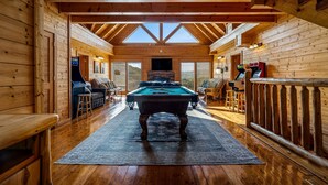 A wooden cabin interior with a pool table, seating area, and a large window. - 8BR with pvt ensuite deck & baths|Views|Pool|Cinema|A+Location|Pets Ok|Sleep 30+ (Sevierville)